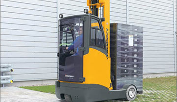 Worker driving Jungheinrich multi-purpose moving mast reach truck transporting materials in back
